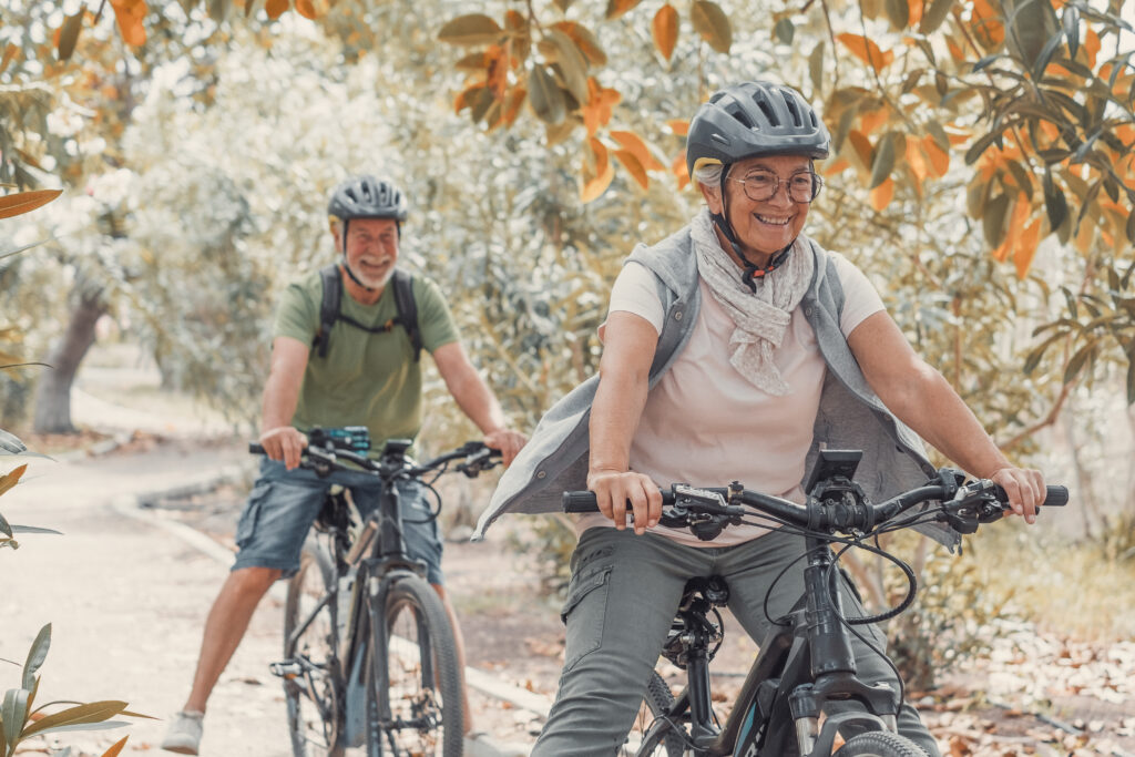 Two happy old mature people enjoying and riding bikes together t
